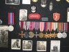 en collage i Stans basement som viser farens medaljer, mærker og billeder fra hans tjeneste med 2nd polish Corps i Afrika og Italien ved Monte Cassino.