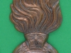 The fur cap badge shown is the cast brass version of that worn by the Royal Regiment of Fusiliers, it was commisioned by RHQ from a manufacturer in Pakistan, being delivered to the Tower of London in January 1980. It replaced a flimsiers truck brass version. The badge is now worn in a shiny gold finished metal with silver coloured St George and wreath. The cast metal one is filled with resin and used as a plaid badge by the regiments Northumbrian Piper. The Fus Bde fur cap badge was a larger version of the wide flamed cap badge in shiny gold and silver coloured metal. 38 x 94mm